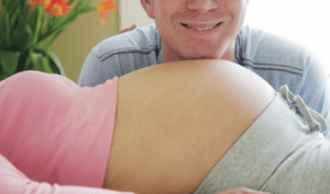 smiling dad with chin on mom's belly